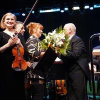 Na zdjęciu władze miasta wręczają kwiaty dyrygentowi orkiestry