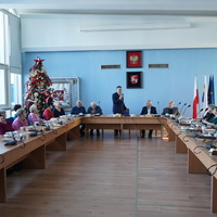 Prezydent Miasta Puławy z mikrofonem, przemawia do grona osób siedzących przy stole.