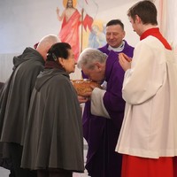 Ksiądz Zeń całuje chleb na rękach przedstawicieli schroniska dla bezdomnych Św. Brata Alberta